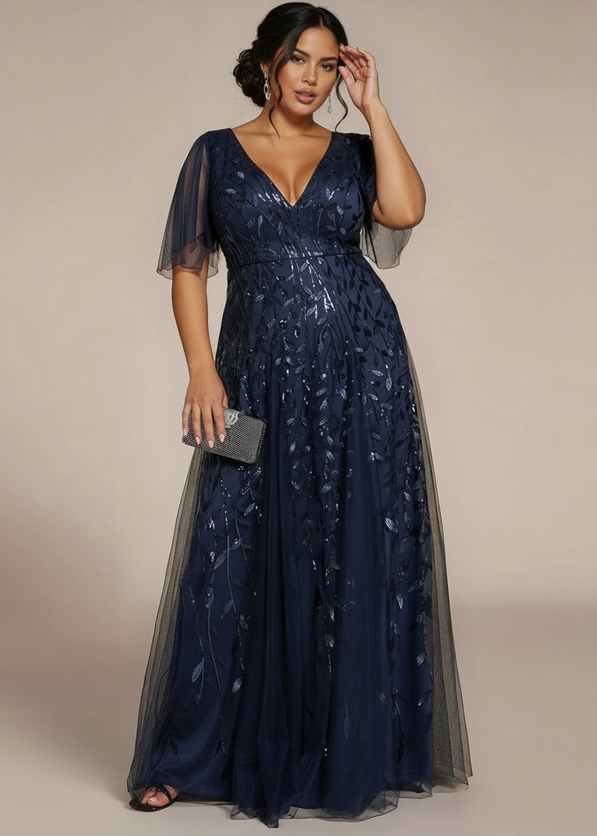 Woman wearing a navy blue evening gown with sheer sleeves against a beige background
