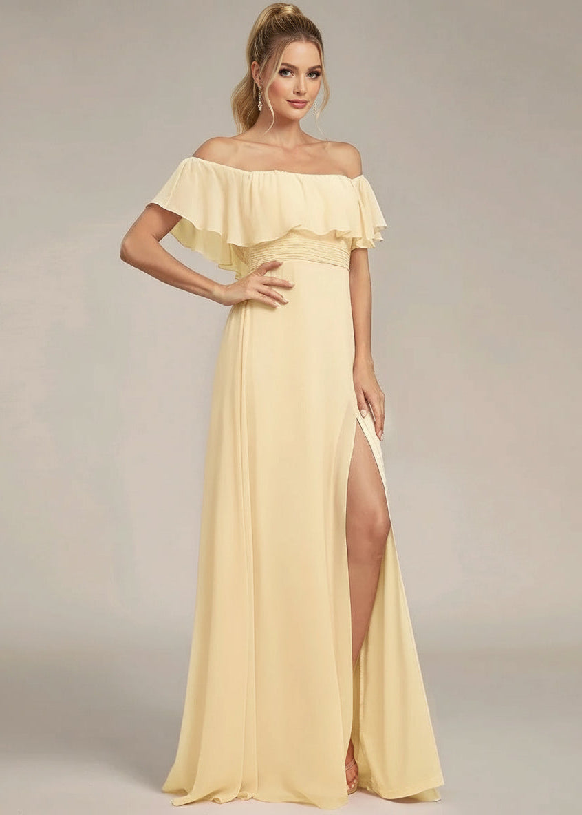 Woman wearing a yellow off-shoulder dress with a slit on a plain background