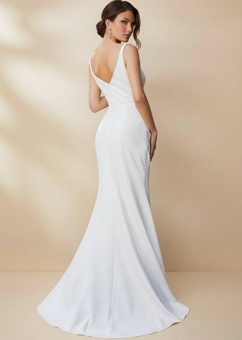 Woman in a white gown standing against a plain background