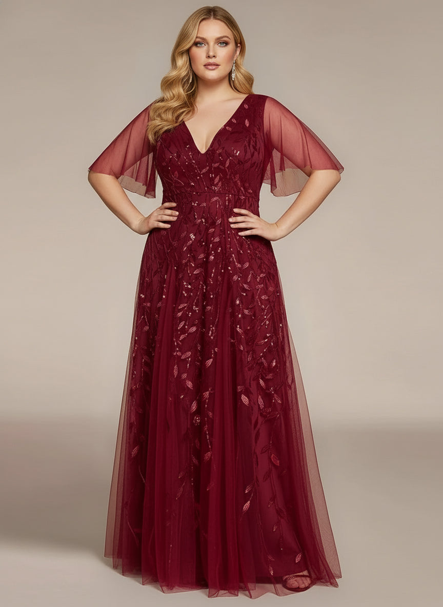 Woman wearing a burgundy evening gown with sheer sleeves against a beige background
