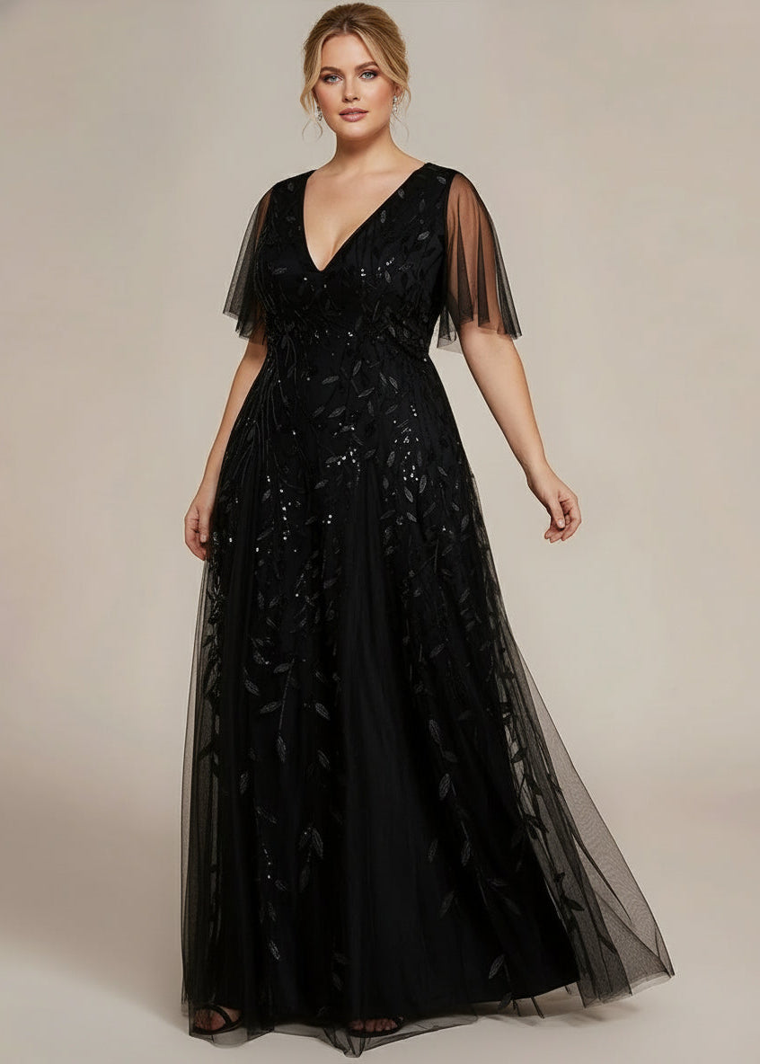 Woman wearing a black evening gown with sheer sleeves against a beige background